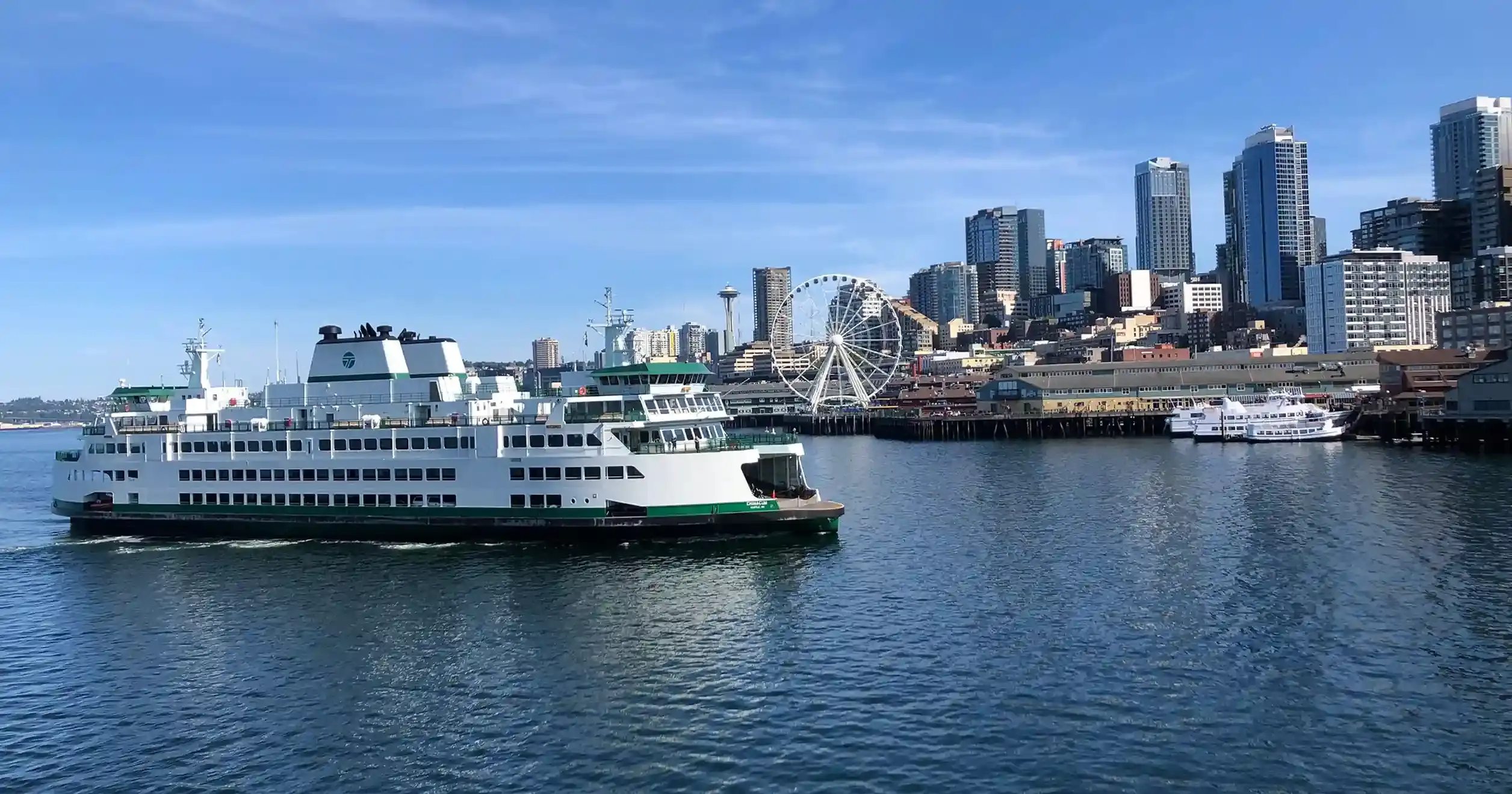A picture of the Seattle skyline on a sunny day as seen from Elliott Bay, with a ferry in the foreground